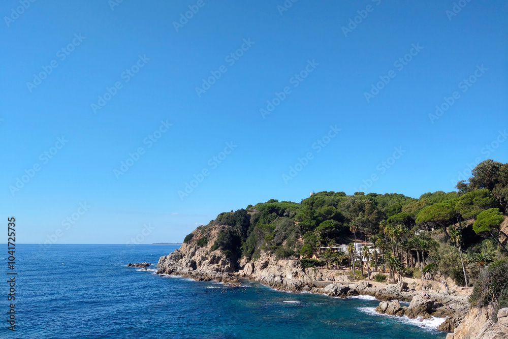 Coastal Landscape with Lush Greenery and Rocky Shoreline on a Clear Day Coastal Landscape with Lush Greenery and Rocky Shoreline on a Clear Day