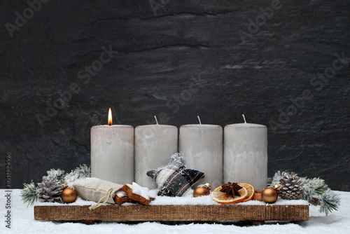 Adventsdekoration: Arrangement für den ersten Advent : Dekoration mit vier grauen Adventskerzen und Weihnachtsschmuck im Schnee.