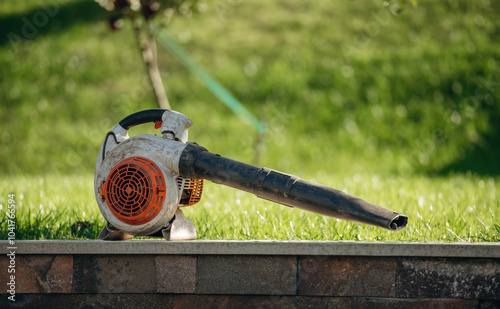 Professional blower is against green lawn with grass, at daytime photo