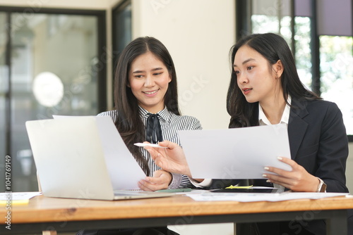 Happy Asian business people working together using laptop and tablet in office.