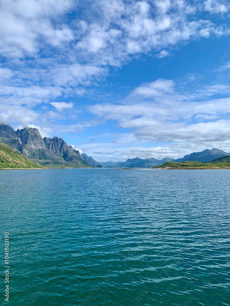Scenic view over a peaceful fjord surrounded by mountains under a partly cloudy sky in Lofoten, Norway Scenic view over a peaceful fjord surrounded by mountains under a partly cloudy sky in Lofoten, Norway