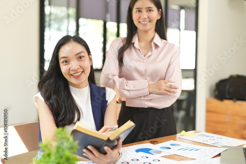 Happy Asian business people working together using laptop and tablet in office.