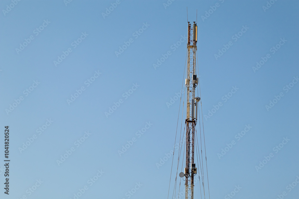 Cellular tower. Telecommunication cell tower against clear blue sky. The structure is equipped with antennas and cables used to transmit the mobile network signal Cellular tower. Telecommunication cell tower against clear blue sky. The structure is equipped with antennas and cables used to transmit the mobile network signal