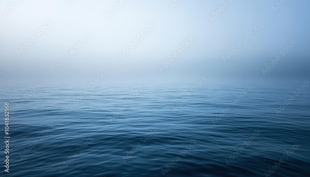 Obraz premium Calm blue ocean waters under a misty sky at dawn near the shoreline