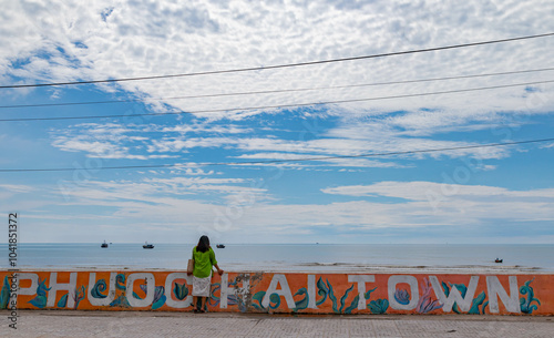 A Girl walks in front of a mural with the word Phuoc Hai Town at in Dat Do District, Bà Rịa–Vũng Tàu province, Vietnam. photo