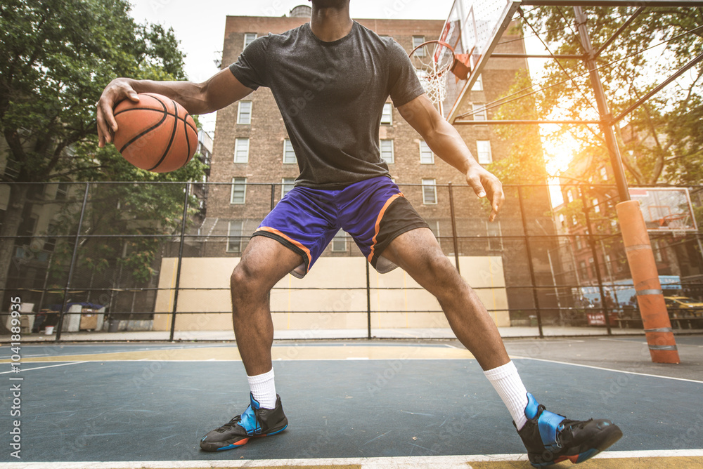 Black sportive basketball player playing basketball on a court in New York City Black sportive basketball player playing basketball on a court in New York City