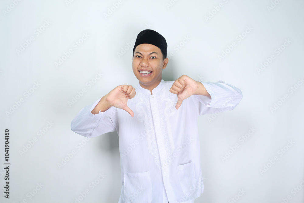 funny muslim asian man giving thumbs down isolated on white background funny muslim asian man giving thumbs down isolated on white background