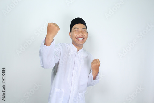 happy muslim asian man raising fist show victory gesture in eid mubarak celebration isolated on white background photo