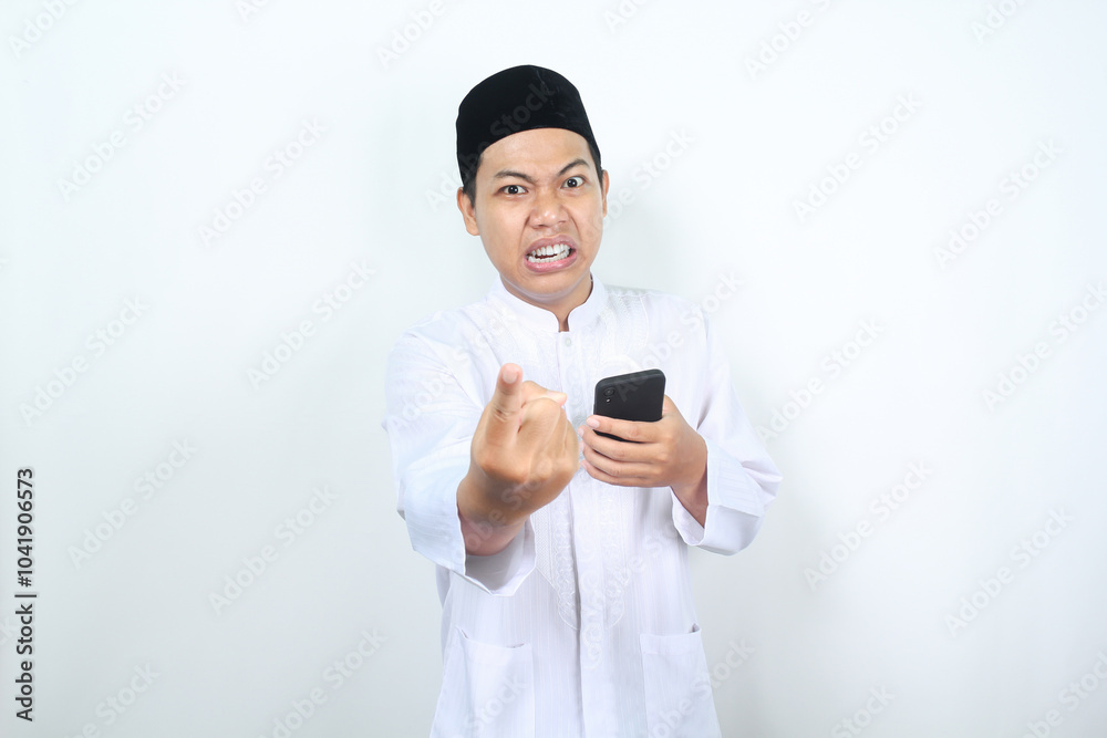 angry muslim asian man pointing forward with holding mobile phone angry muslim asian man pointing forward with holding mobile phone