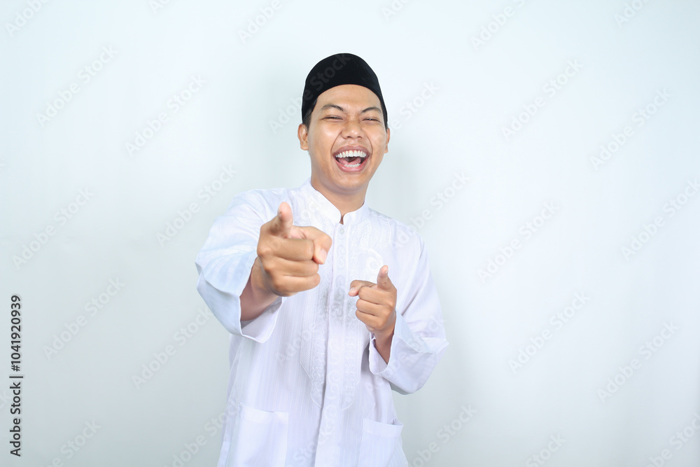 laughing asian muslim man pointing at camera isolated on white background