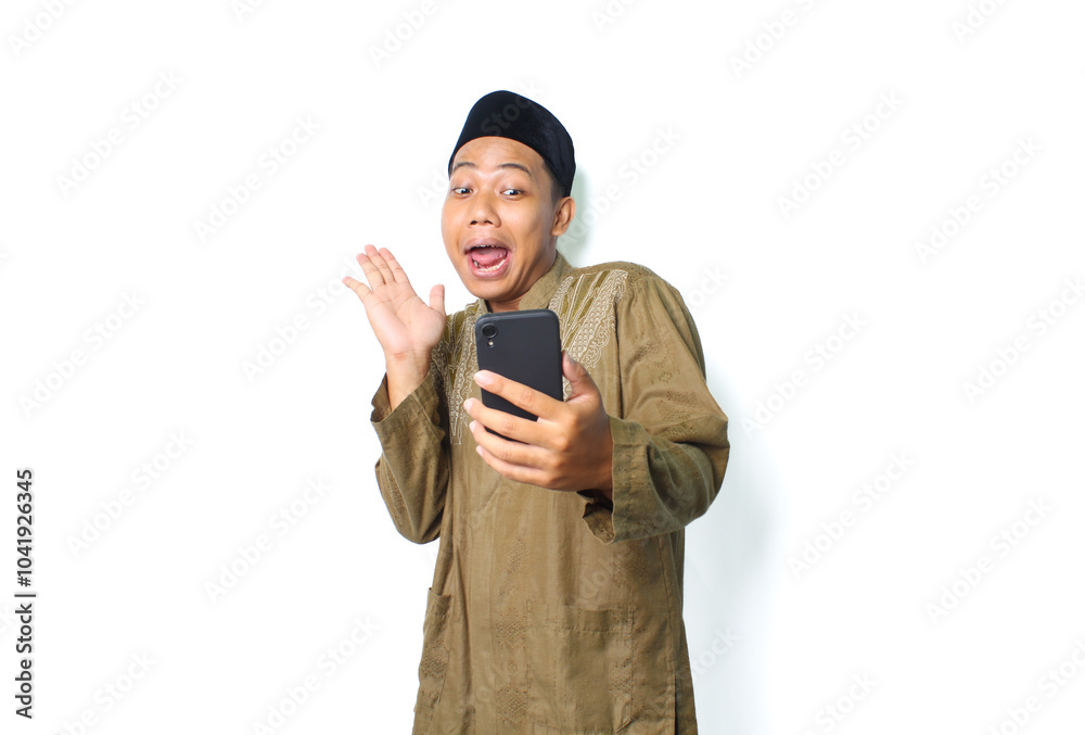 funny asian muslim man wearing islamic dress holding mobile phone raising hand looks surprised isolated on white background funny asian muslim man wearing islamic dress holding mobile phone raising hand looks surprised isolated on white background