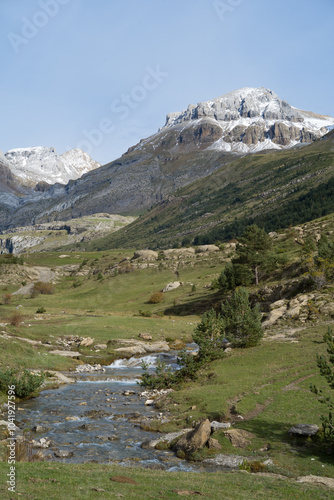 Primer plano del río Estarrún discurriendo por el valle de Aísa con la cumbre de Llena de la Garganta al fondo tras recibir la primera nevada de otoño