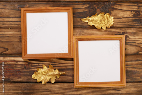 Two square frames with copy space for your images or text, decorated with golden oak leaves on the background of an old fire-treated wooden wall