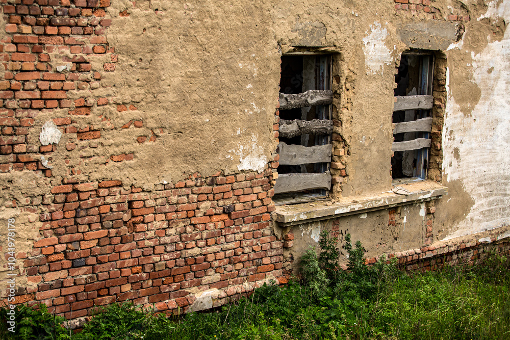 A brick wall constructed with several windows that are currently boarded up A brick wall constructed with several windows that are currently boarded up