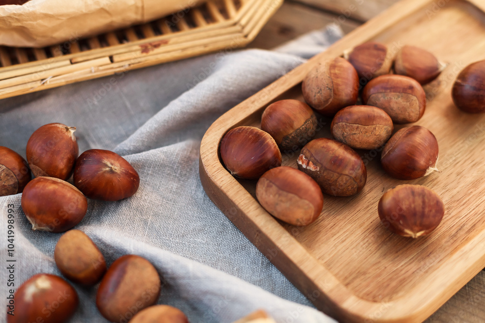 wooden table topped with trays of fresh and toasted chestnuts a person holding roasted chestnuts