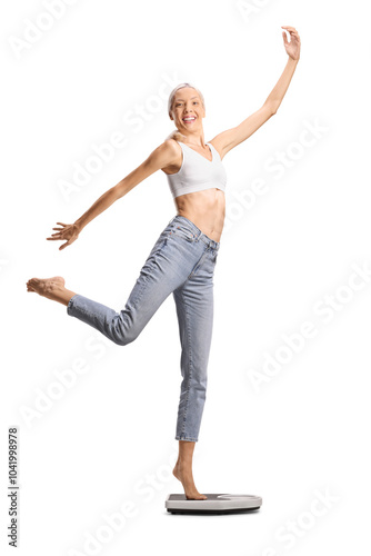 Tall slim woman in jeans and white crop top dancing on a weight scale