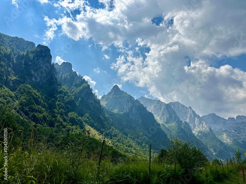 Dramatic mountain peaks with bright blue sky and clouds in the background