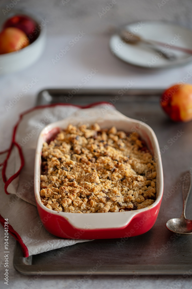 Crumble, Crisp or Cobbler with nectarines, peaches and rolled oats in casserole dish on a metal tray. American cuisine. Easy dessert.