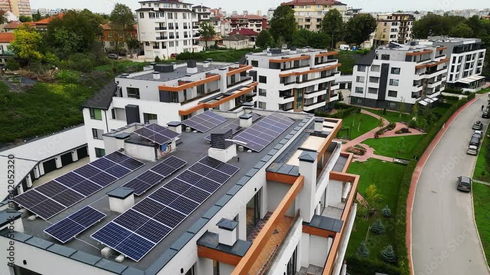 Aerial view of modern apartment buildings with solar panels on the roofs. The green surroundings and well-maintained pathways add to the eco-friendly urban landscape Aerial view of modern apartment buildings with solar panels on the roofs. The green surroundings and well-maintained pathways add to the eco-friendly urban landscape