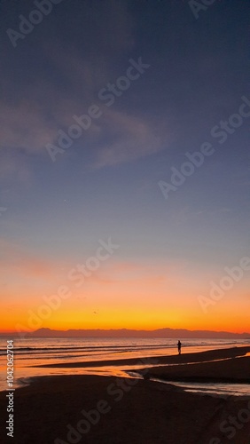 Silhouette of a man at sunset by the sea. wonderful colorful sunset on a calm sea with shore