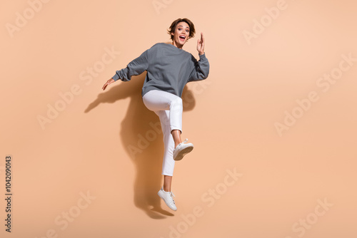 Full length photo of active positive girl wear oversize pullover white trousers jumping run shopping isolated on pastel color background