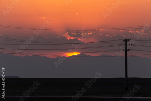 Silhouette of power line in a desert with a perfect background of sunset in a cloudy sky. photo