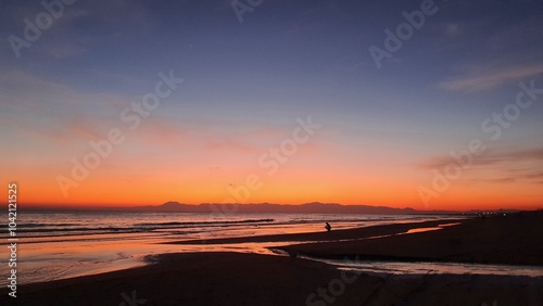 Silhouette of a man at sunset by the sea. wonderful colorful sunset on a calm sea with shore