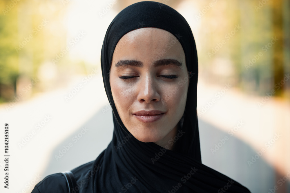 Confident woman with hijab standing with eyes closed standing in the city Confident woman with hijab standing with eyes closed standing in the city