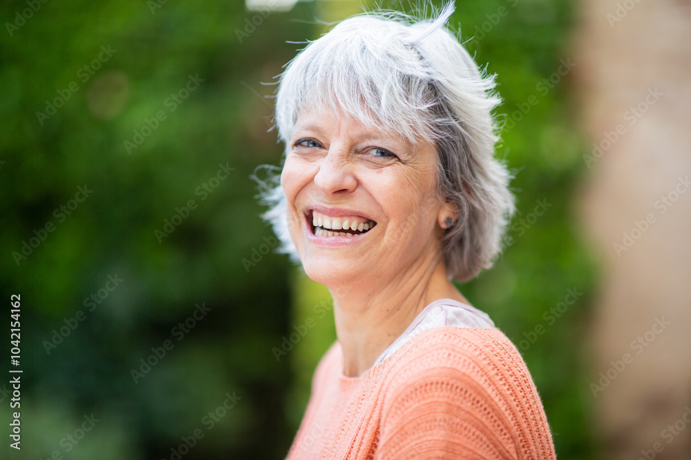 Laughing older woman in orange sweater during outdoor portrait Laughing older woman in orange sweater during outdoor portrait