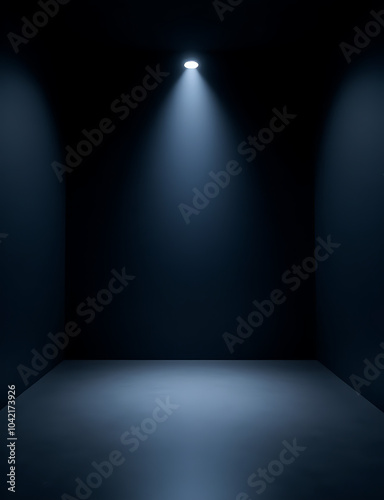 A small black box theater stage with no set, plain black walls, and a single soft blue spotlight illuminating the center.