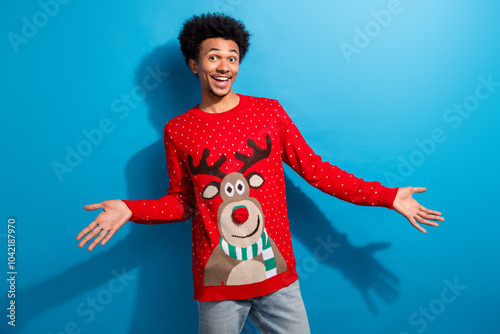 Photo portrait of attractive young man excited reaction hello dressed red christmas sweater theme party on blue color background photo