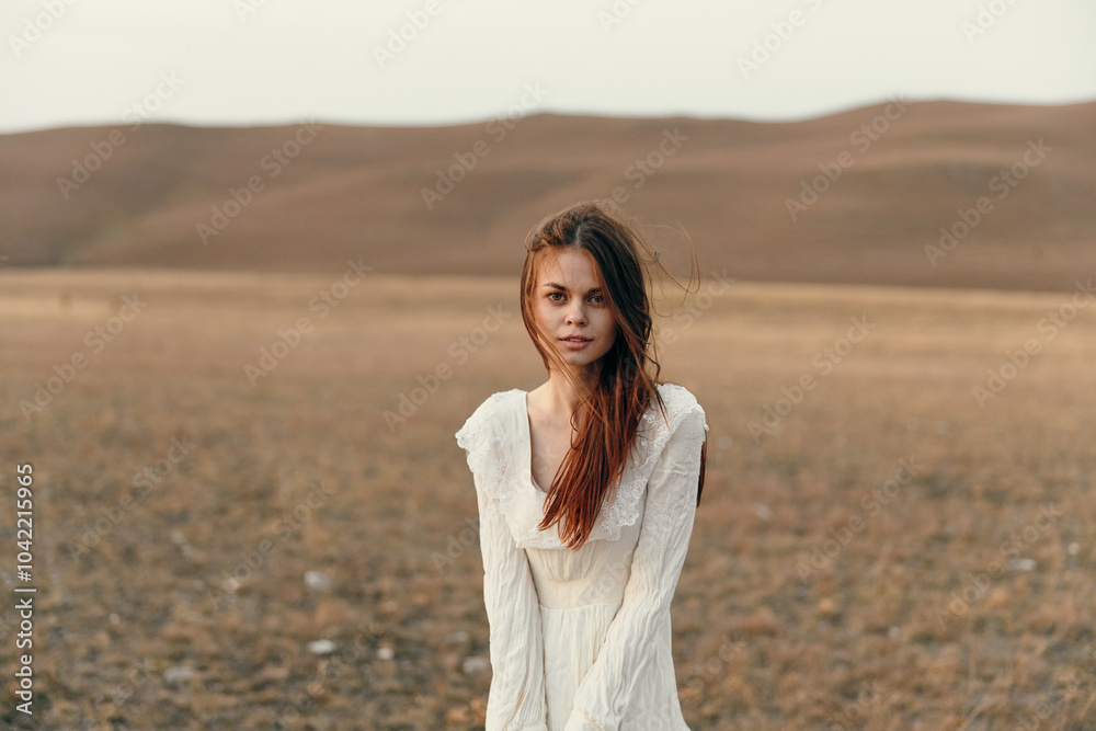 Woman in white dress standing in vast open field with hands on hips in fashionable pose beauty and nature concept Woman in white dress standing in vast open field with hands on hips in fashionable pose beauty and nature concept