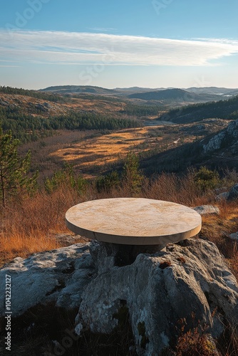 Scenic overlook with a circular stone table amidst hills and valleys at sunse...