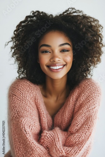 Young woman in a pink sweater smiles warmly against a snowy winter backdrop a...