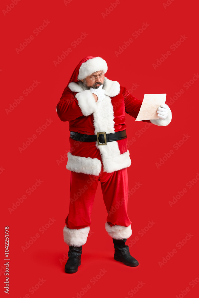 Thoughtful Santa Claus reading letter on red background Thoughtful Santa Claus reading letter on red background