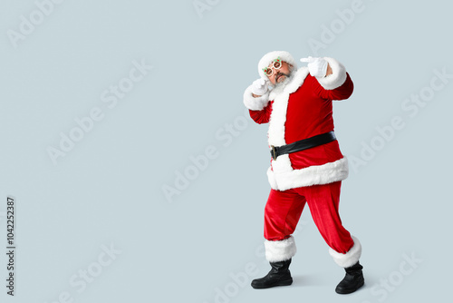 Funny Santa Claus dancing on grey background