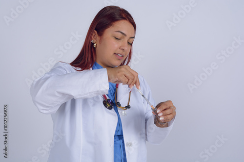 Latin woman doctor preparing the solution to inject the patient, studio shot, white background photo