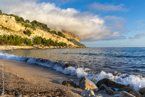 The evening sun illuminates the cliffs shrouded in clouds above the sea level