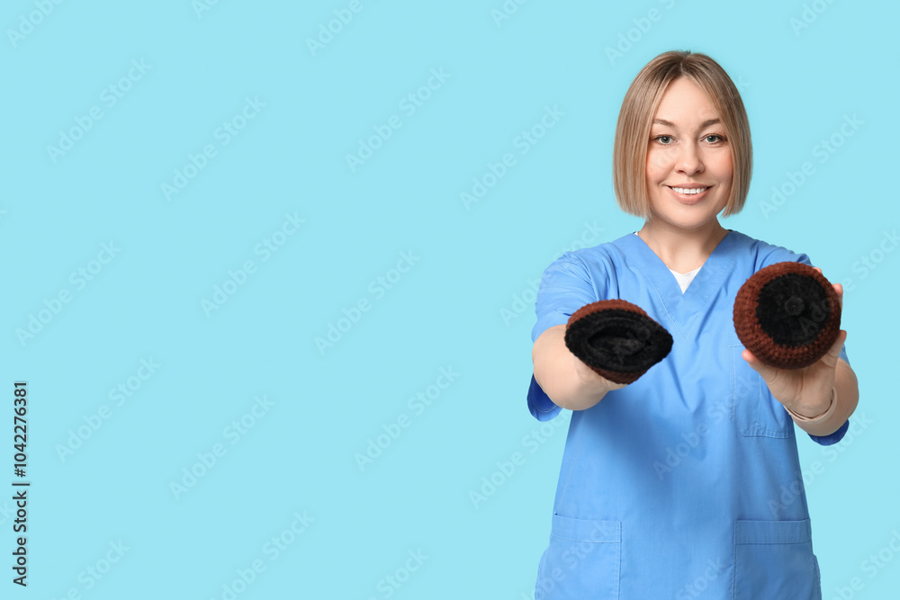 Mature happy female doctor with knitted model of breast on blue background. Breast feeding concept Mature happy female doctor with knitted model of breast on blue background. Breast feeding concept