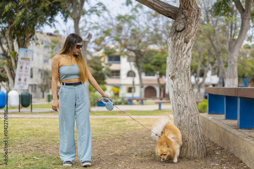 Young woman walking with her dog on leash in a park