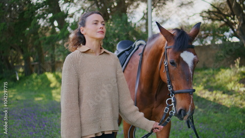 Horsewoman strolling pet relaxing together in park closeup. Woman holding bridle