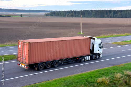 Semi Truck transport the sea container on highway. Shipping Containers Delivery by road, Maritime Services and Transport logistics. Soft focus possible granularity photo