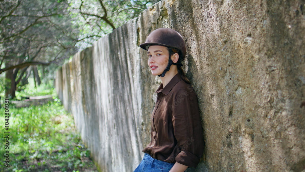 Jockey lady leaning fence at ranch area portrait. Woman in helmet looking camera Jockey lady leaning fence at ranch area portrait. Woman in helmet looking camera