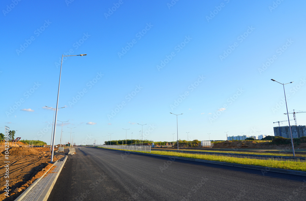 Fototapeta premium Asphalt road after laying asphalt. New asphalt road renovation. Road construction. Paved highway. Black tarmac road after rebuilding, repair, renovation. Black tarmac rebuilding. Street Asphalting.