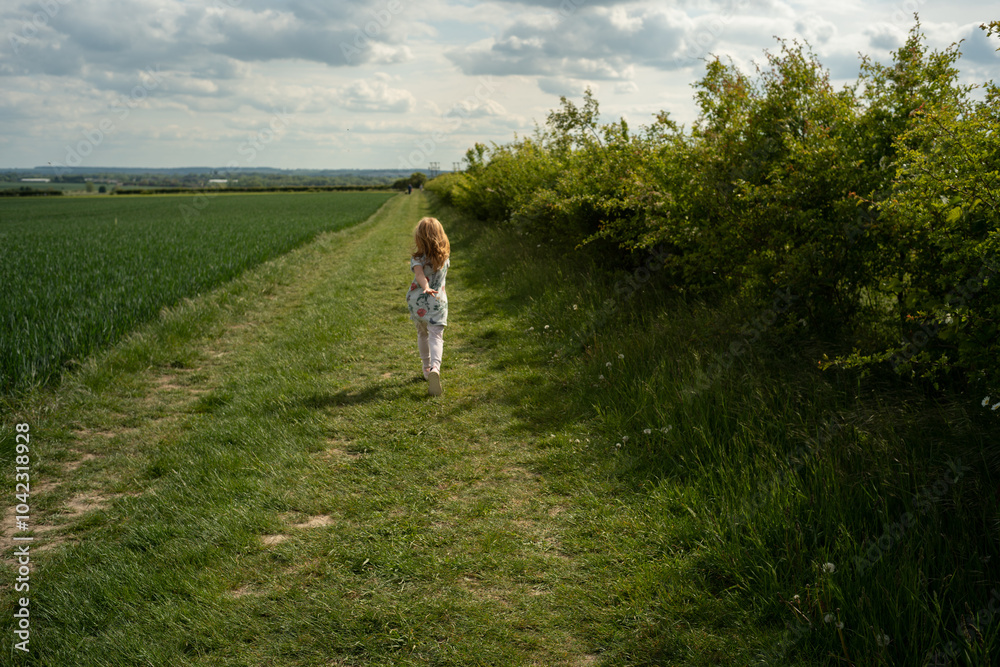 little ginger-haired girl runs in the field with green grass little ginger-haired girl runs in the field with green grass