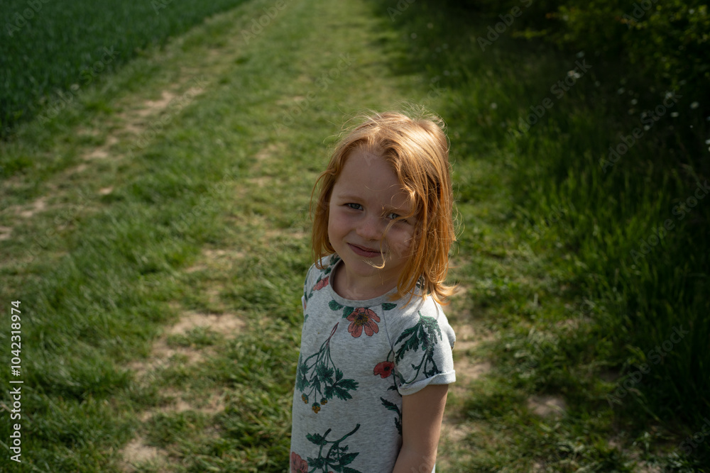 little ginger-haired girl in the field with green grass little ginger-haired girl in the field with green grass