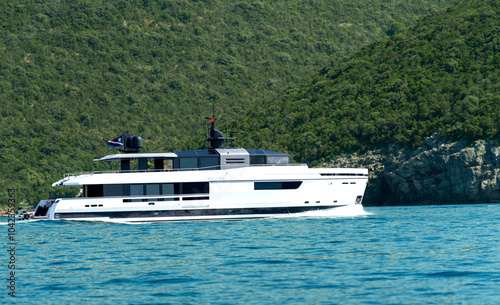 Big yacht or boat in bright blue sea against green cliff