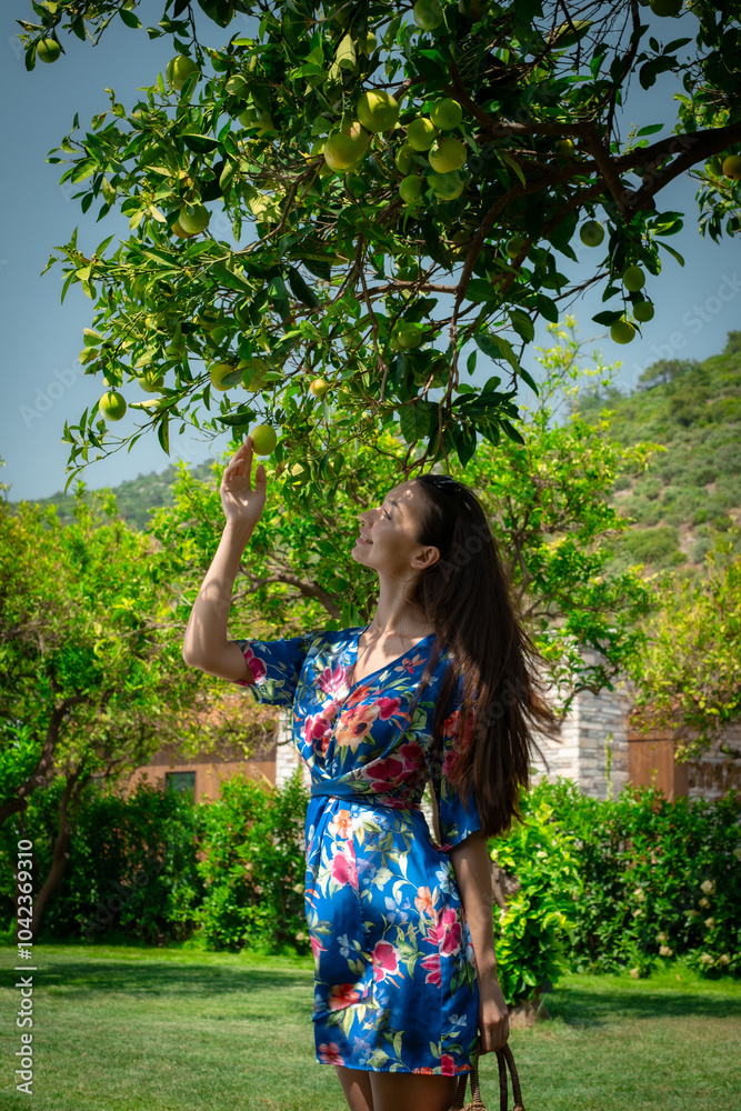 A woman peacefully walking between vibrant lemon trees, enjoying the fresh, natural surroundings, creating a calm and serene atmosphere in a garden. A woman peacefully walking between vibrant lemon trees, enjoying the fresh, natural surroundings, creating a calm and serene atmosphere in a garden.