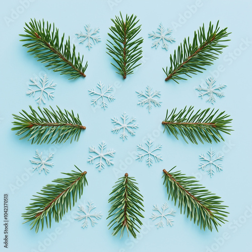 green pine leaves and snowflakes on a light blue background.Minimal creative Christmas holiday concept.Flat lay 