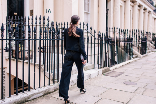 Business woman in black pantsuit and high heels walks briskly down the street in London